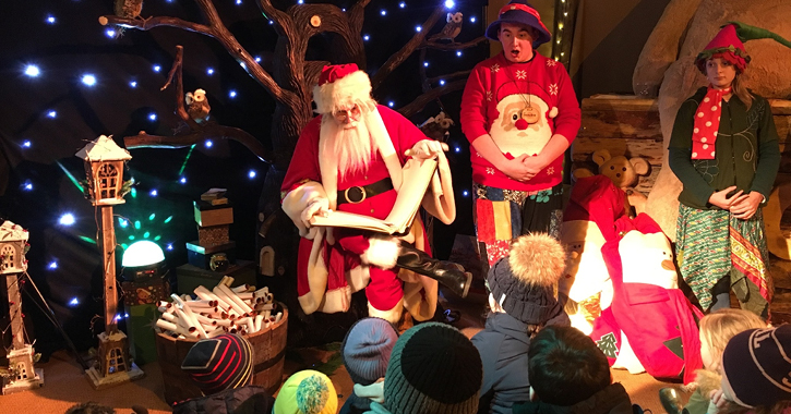 Santa reads a story with children at his feet at Believe, Hardwick Hall Hotel